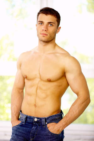 Muscular and tanned male standing near the window