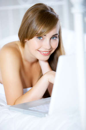 Beautiful teenager on white bed at her homeの写真素材