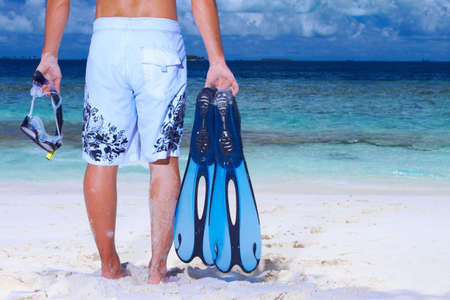 Handsome man on the beach holding fin and pipeの写真素材