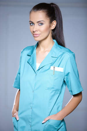 Portrait of beautiful female doctor on gray backgroundの写真素材