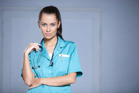 Portrait of beautiful female doctor on gray backgroundの写真素材