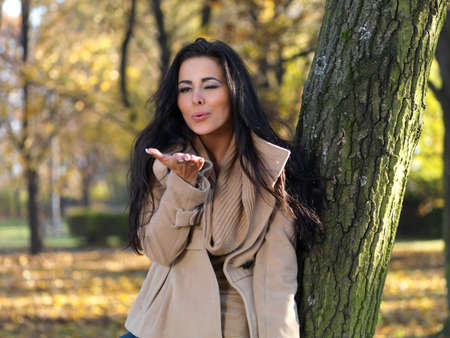 Beautiful woman spending time in park during autumn seasonの写真素材