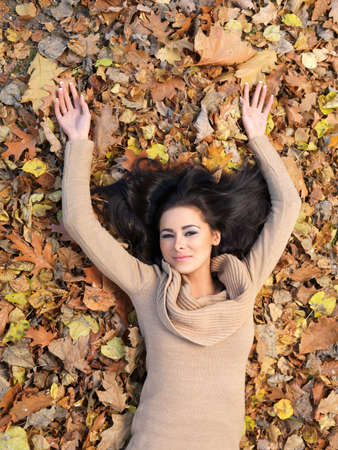 Beautiful woman spending time in park during autumn seasonの写真素材