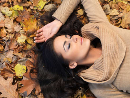 Beautiful woman spending time in park during autumn seasonの写真素材
