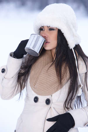 Beautiful holding mug in snowy winter outdoorsの写真素材