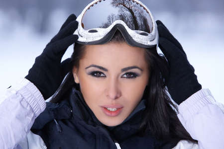 Beautiful woman wearing goggles in snowy winter outdoorsの写真素材