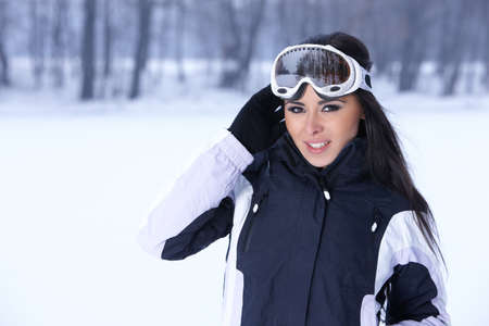Beautiful woman wearing goggles in snowy winter outdoorsの写真素材