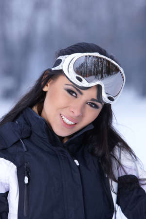 Beautiful woman wearing goggles in snowy winter outdoorsの写真素材
