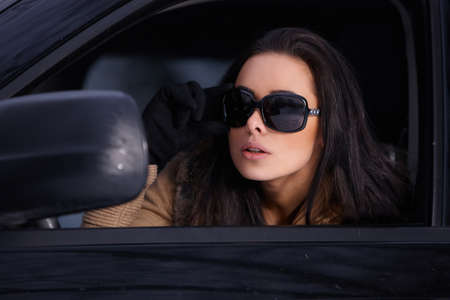 Beautiful woman in car in snowy winter outdoorsの写真素材