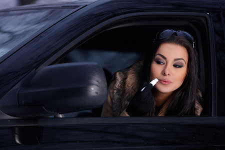 Beautiful woman in car in snowy winter outdoorsの写真素材