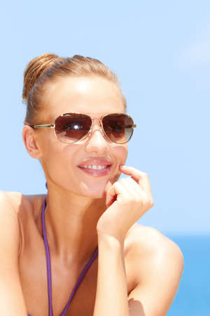 Pretty young woman at the beach with sunglassesの写真素材