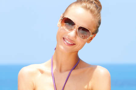 Pretty blond female with sunglasses on at the beachの写真素材