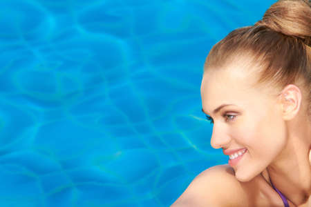 Portrait of smiling beauty on pool blue water backgroundの写真素材