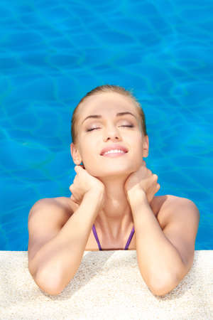 Dreaming woman with eyes closed in swimming poolの写真素材