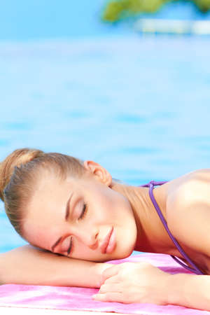 Young beautiful woman sleeping next to swimming poolの写真素材