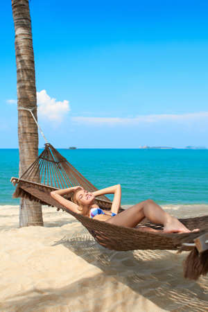 Woman tourist on a summer vacation enjoying the serenity of a tropical beach at a waterfront retreatの写真素材