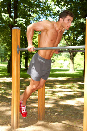Fine looking young guy doing excercises in parkの写真素材