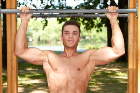 Good looking male doing exercises in park at summer timeの写真素材