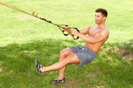 Muscular male doing stretch exercises in parkの写真素材