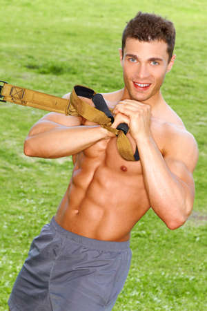 Muscular male doing stretch exercises in parkの写真素材