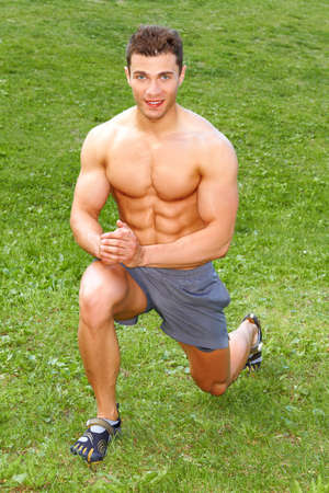 Handsome man doing stretch exercises on grassの写真素材