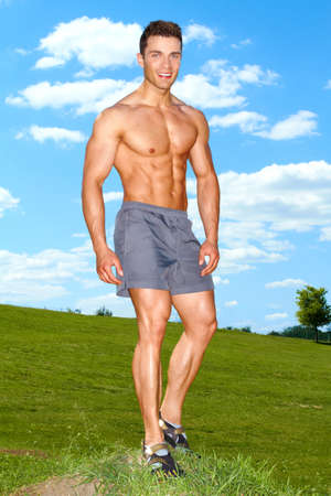 Full body of muscular man standing on grass at the parkの写真素材