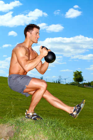 Man Exercises with kettlebell in sunny weatherの写真素材