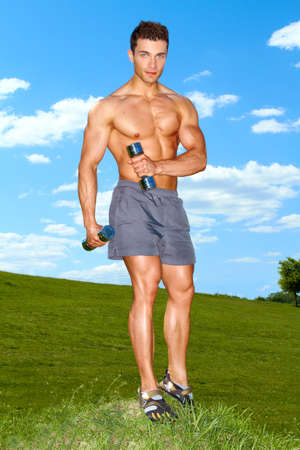 Fullbody of male working with dumbbels at outdoorの写真素材