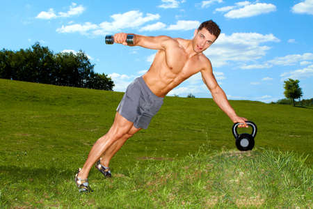 Fitness man practicing with weights at the parkの写真素材