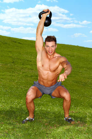 Man Exercises with kettlebell in sunny weatherの写真素材