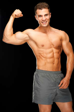 Portrait of confident muscular man flexing his biceps on black backgroundの写真素材