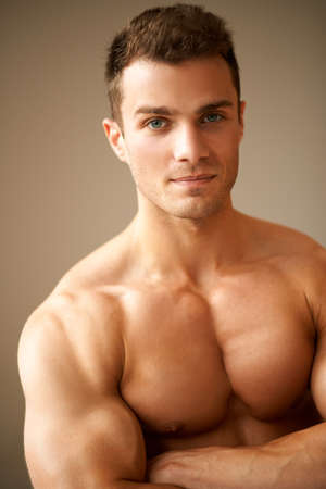 Close up of sporty man with muscular arms crossed on brown backgroundの写真素材