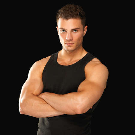Happy fit male with arms crossed posing over black backgroundの写真素材