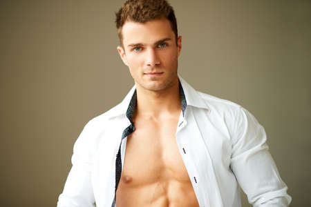 Portrait of muscular man posing in white shirt over brown backgroundの写真素材