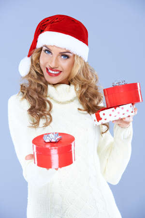 Pretty blond woman in Santa hat holding Christmas giftsの写真素材