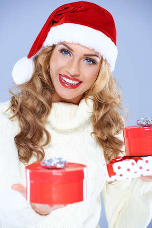 Close up of smiling woman in Santa hat holding Christmas giftsの写真素材