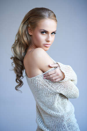 Pretty blonde girl posing while isolated against a grey backgroundの写真素材