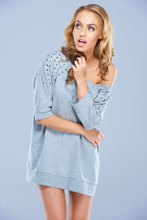 Portrait of cute young female posing on gray backgroundの写真素材