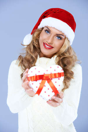 Close up of smiling woman in Santa hat holding Christmas giftの写真素材