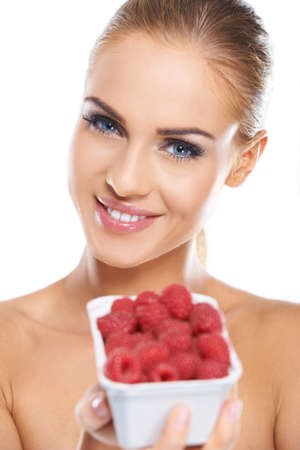 Close up of smiling blonde holding raspberries while isolatedの写真素材