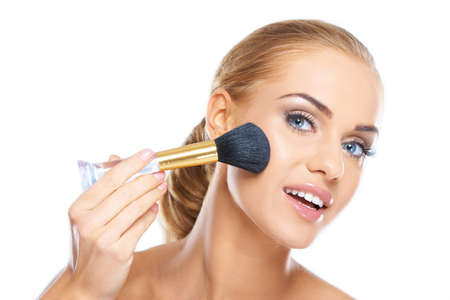 Portrait of a beautiful young blonde applying makeup to her faceの写真素材