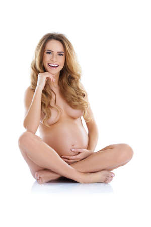 Portrait of a pregnant young woman with a visible belly, sitting isolatedの写真素材