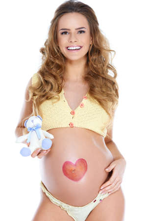 Young pregnant woman with heart shape pained on her bellyの写真素材