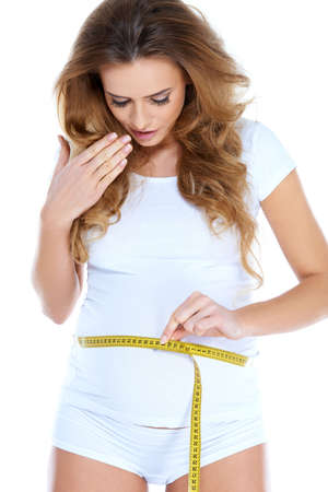Pregnant woman measurig her belly while isolatedの写真素材