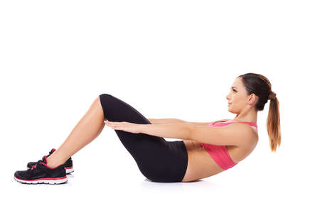 Fit young woman working out in a gym doing sit ups to strengthen her abdominal muscles on whiteの写真素材