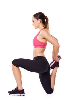 Woman athlete doing a workout kneeling to flex and stretcg her leg muscles for improved mobility, studio portrait on whiteの写真素材