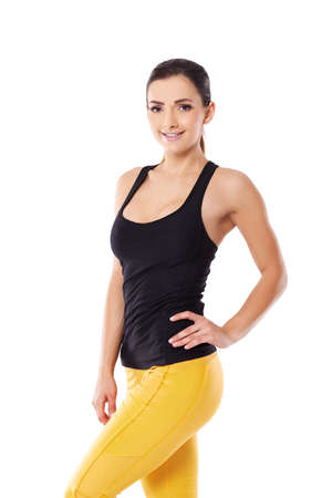Beautiful sexy woman in yellow gym tights smiling at the camera with her hand on her hip accentuating her fit shapely bodyの写真素材