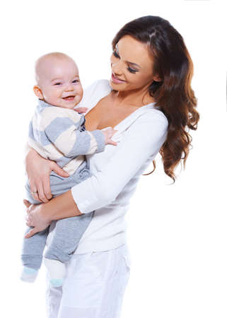 Beautiful young mother with a happy baby who is beaming at the camera clasped in her arms isolated on whiteの写真素材