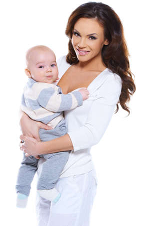 Smiling attractive young mother clasping her cute chubby her young baby in her arms isolated on whiteの写真素材