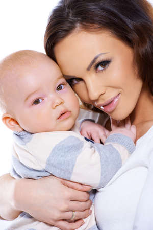 Cute little baby being held in a close embrace by a loving mother, studio portrait isolated on whiteの写真素材